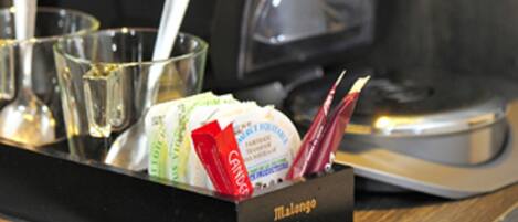 Une machine à café avec un plateau contenant des condiments et des ustensiles.