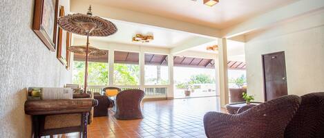 A spacious indoor area with wicker furniture, a tiled floor, and ceiling lights.
