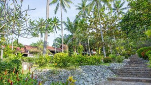 A stone staircase leading up to a building with a red roof, surrounded by lush greenery and palm trees. - Nova Samui Resort (Koh Samui)