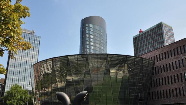 Un edificio moderno con fachada de vidrio curvada y una torre cilíndrica.