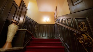 Un magnifique escalier avec des marches recouvertes de moquette rouge et des lambris en bois foncé.