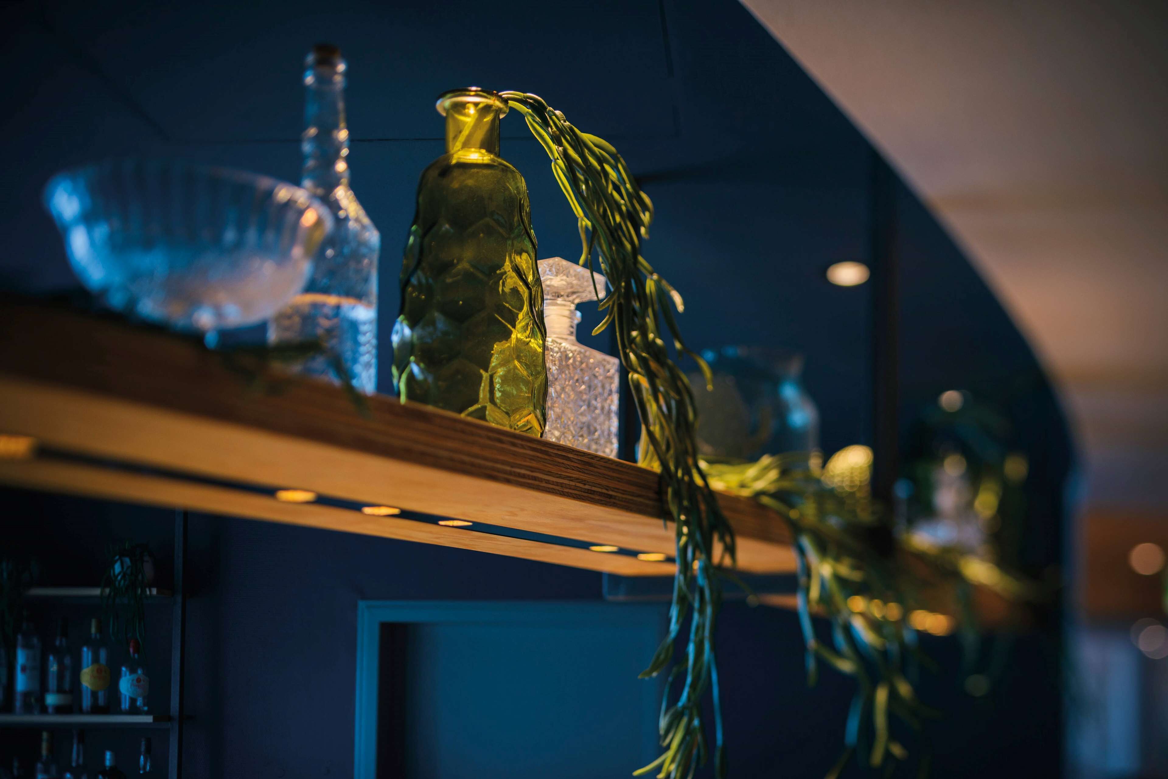 A bar area with shelves holding various bottles and glasses.