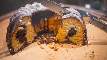 A bundt cake with a knife cutting through it, placed on a wooden surface.