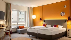 Una habitación de hotel con cama, escritorio, silla, mesita y ventana.