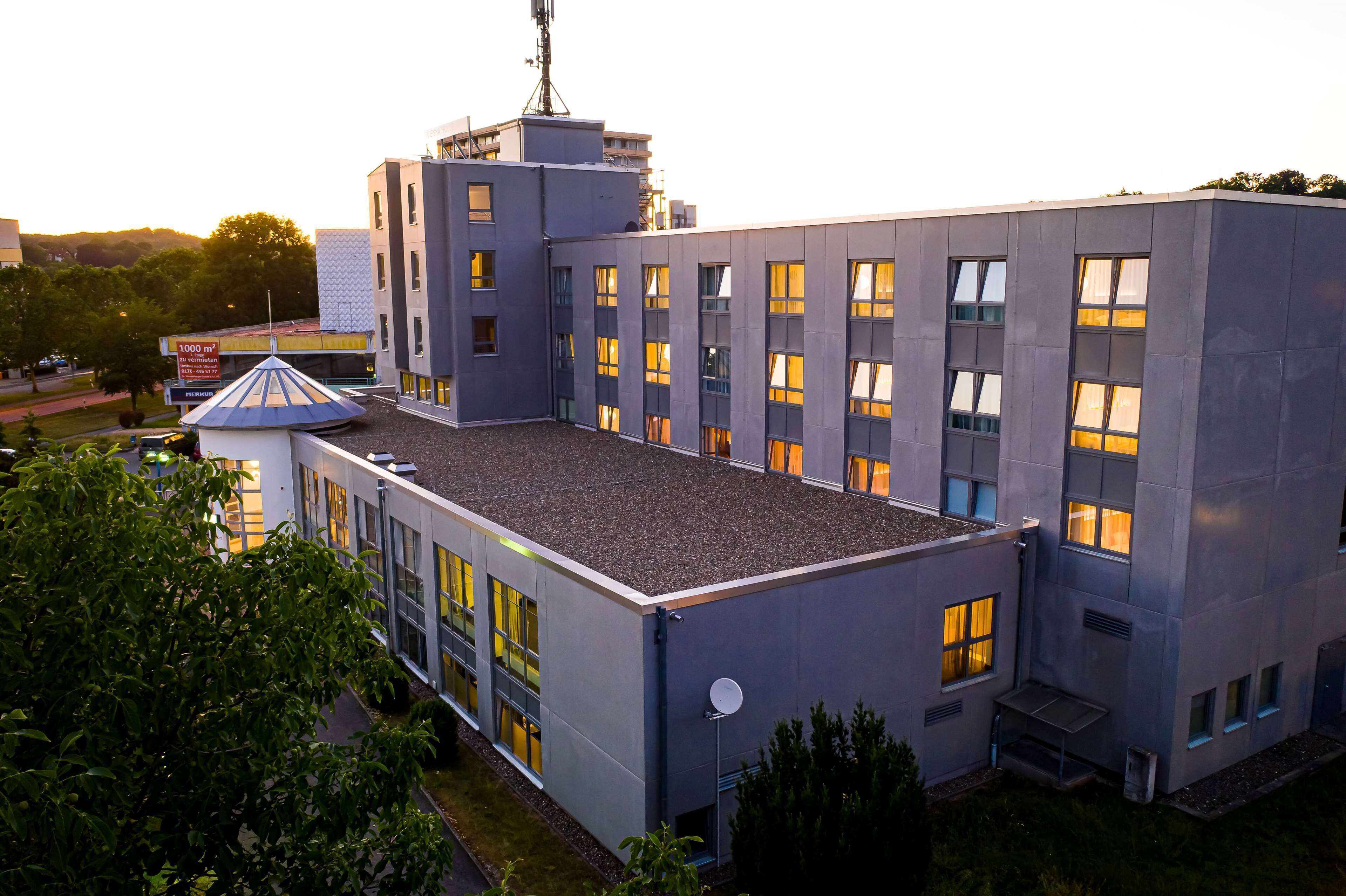 Un edificio moderno con techo plano, varias ventanas y una antena parabólica.