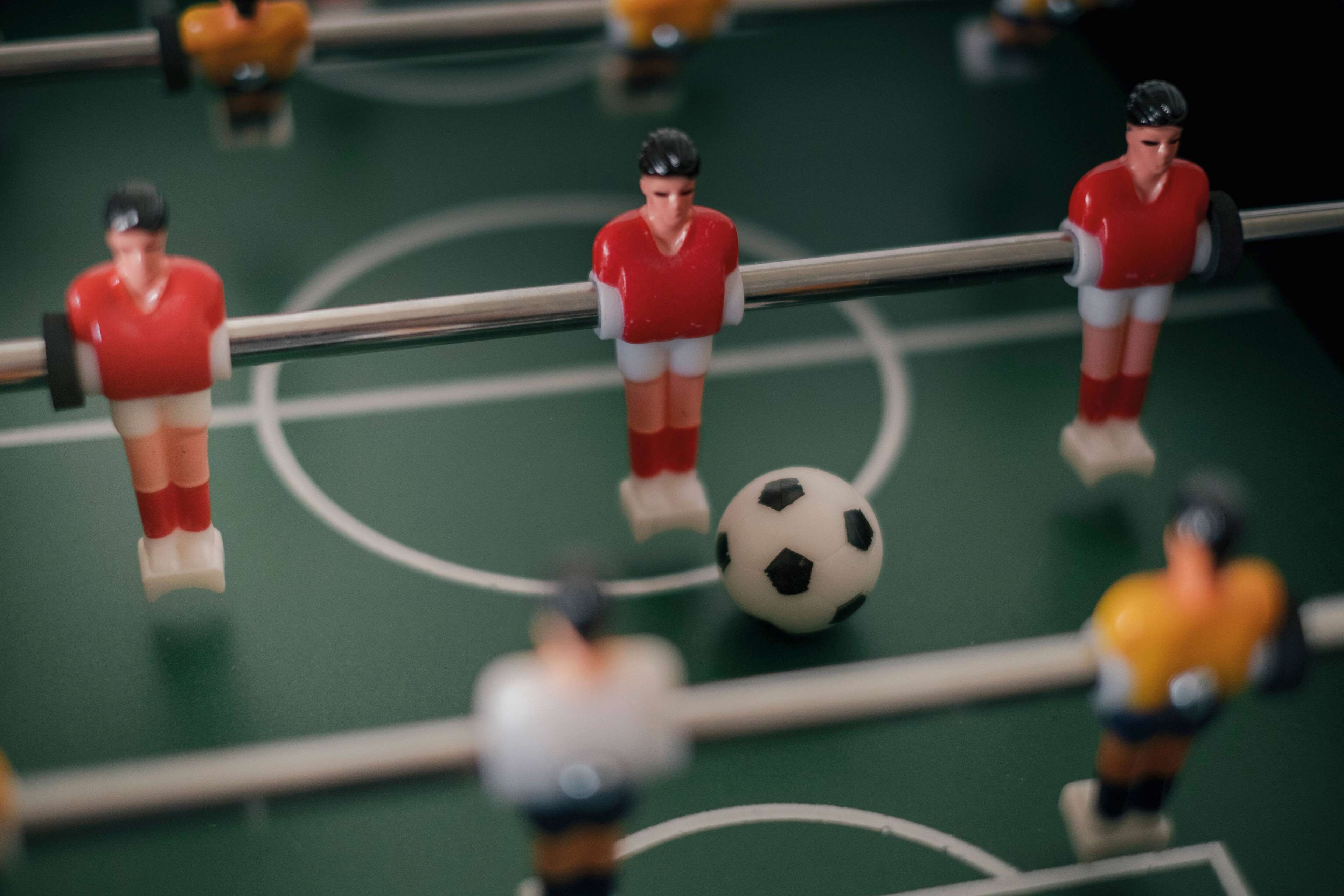 A miniature soccer field with figurines in red and yellow uniforms.