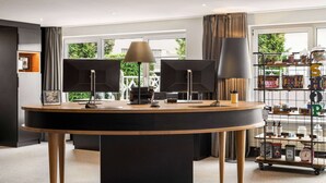 Una habitación moderna con una mesa redonda, dos lámparas negras y un estante con diversos objetos.