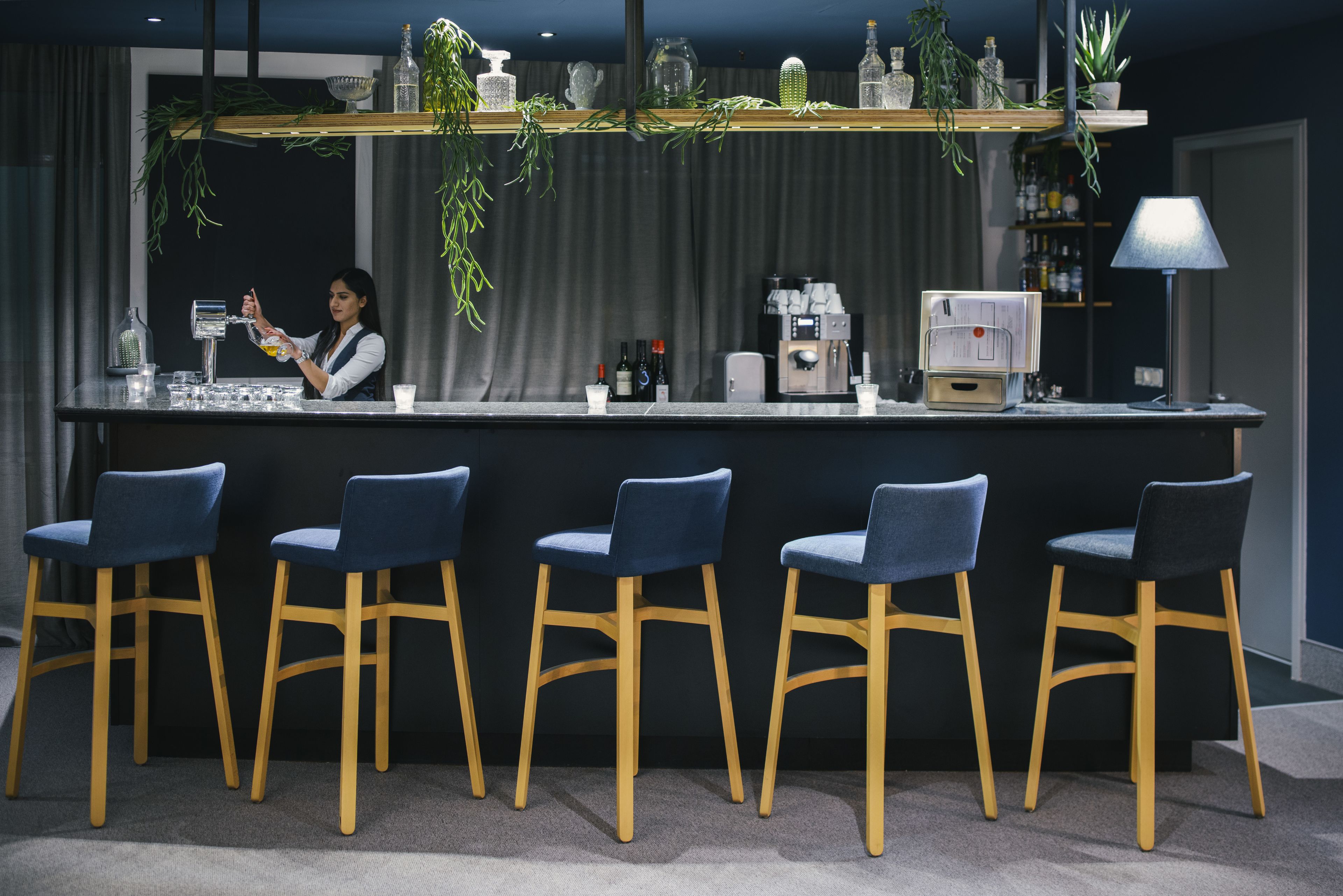 A bar area with a bartender, bar counter, and seating.