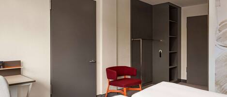 Una habitación de hotel con cama, escritorio, silla y armario.
