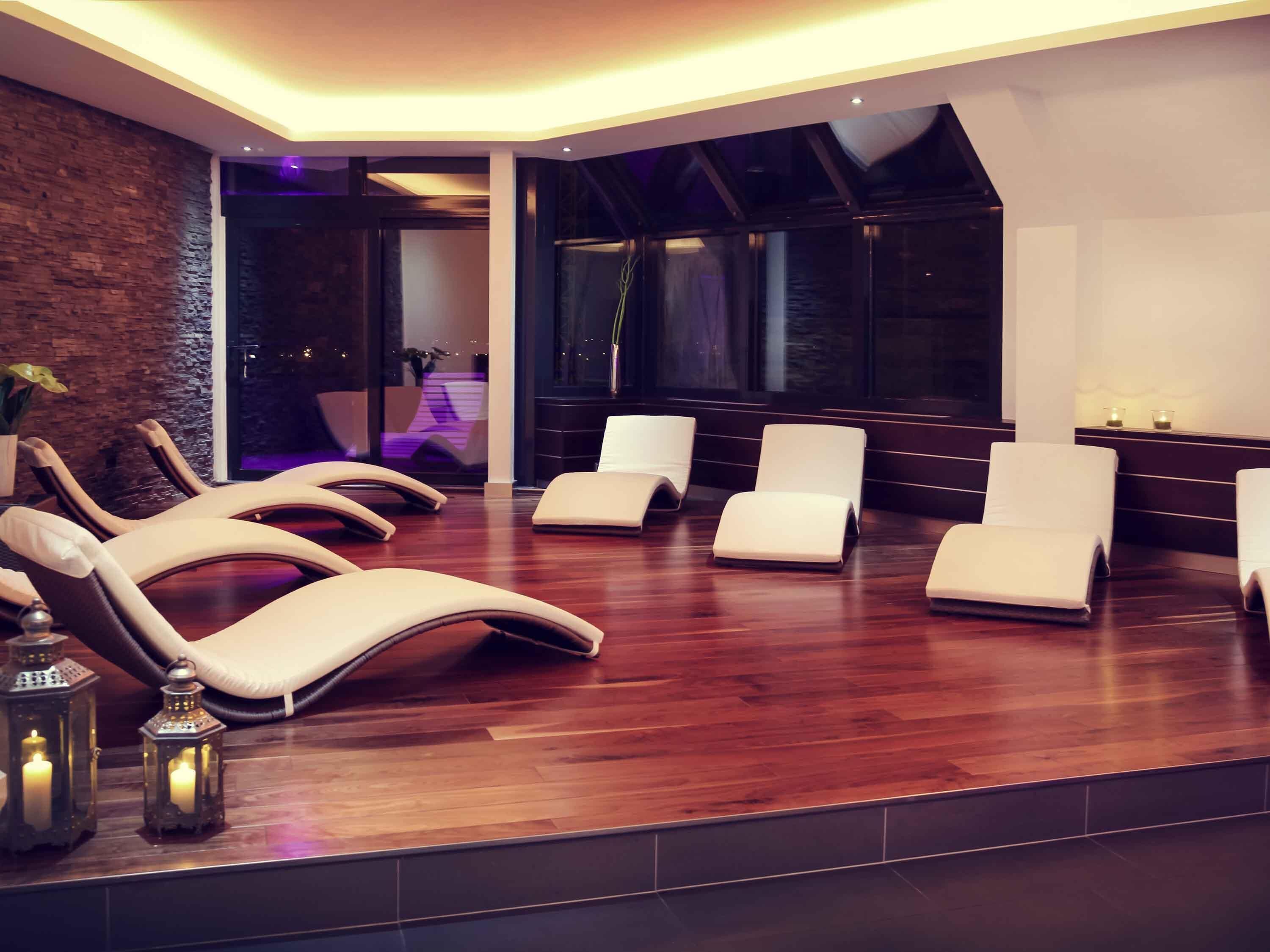 A modern spa room with reclining chairs, a wooden floor, and a brick wall.