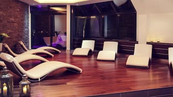 A modern spa room with reclining chairs, a wooden floor, and a brick wall.
