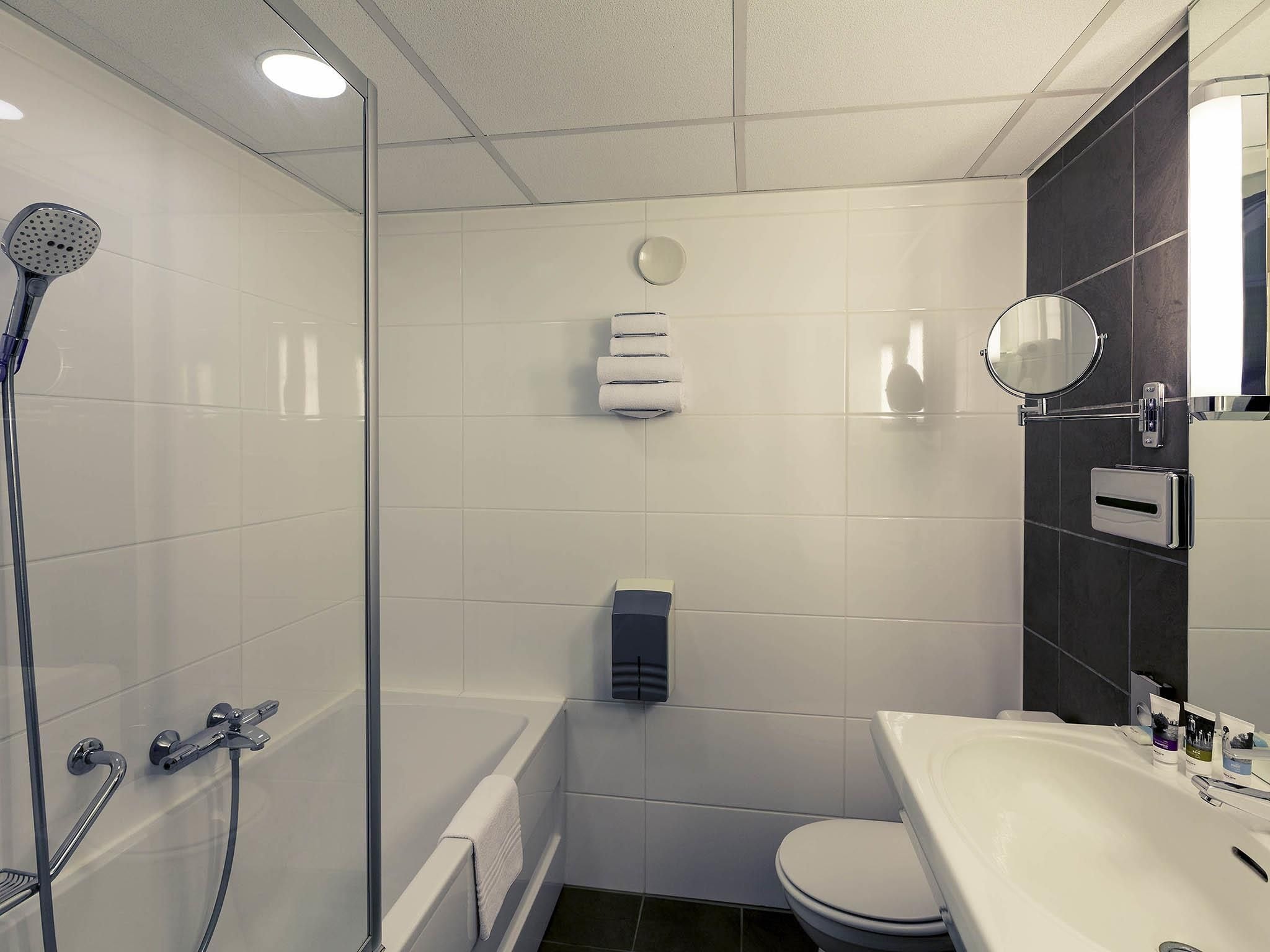 Un baño moderno con ducha de vidrio, inodoro blanco y lavamanos con espejo.