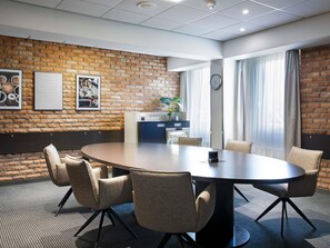 Ein Konferenzraum mit Backsteinwand, einem runden Tisch und sechs Stühlen.