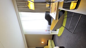 Een kleine hotelkamer met een bed, een bureau en een raam.