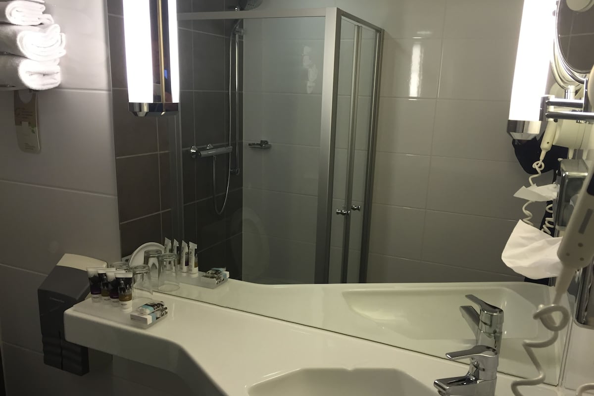 Een moderne badkamer met een grote spiegel, een wastafel en een douche.