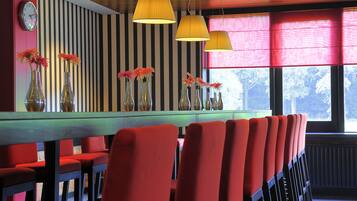 Une salle de conférence avec une longue table, des chaises rouges et des lampes suspendues.