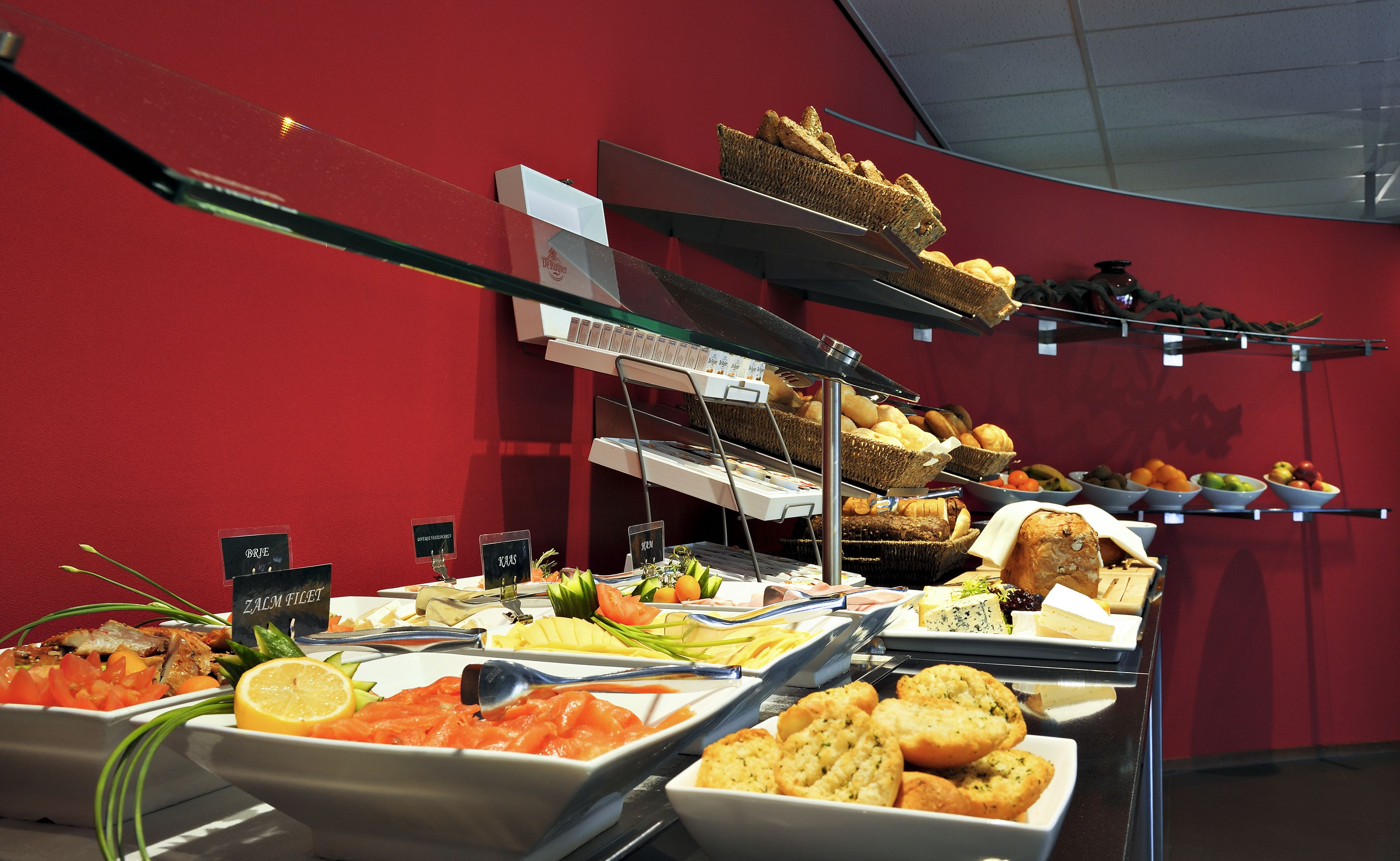 A buffet with various food items including salmon, bread, and fruits.