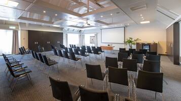 A conference room with rows of chairs, a projector screen, and a presentation area.