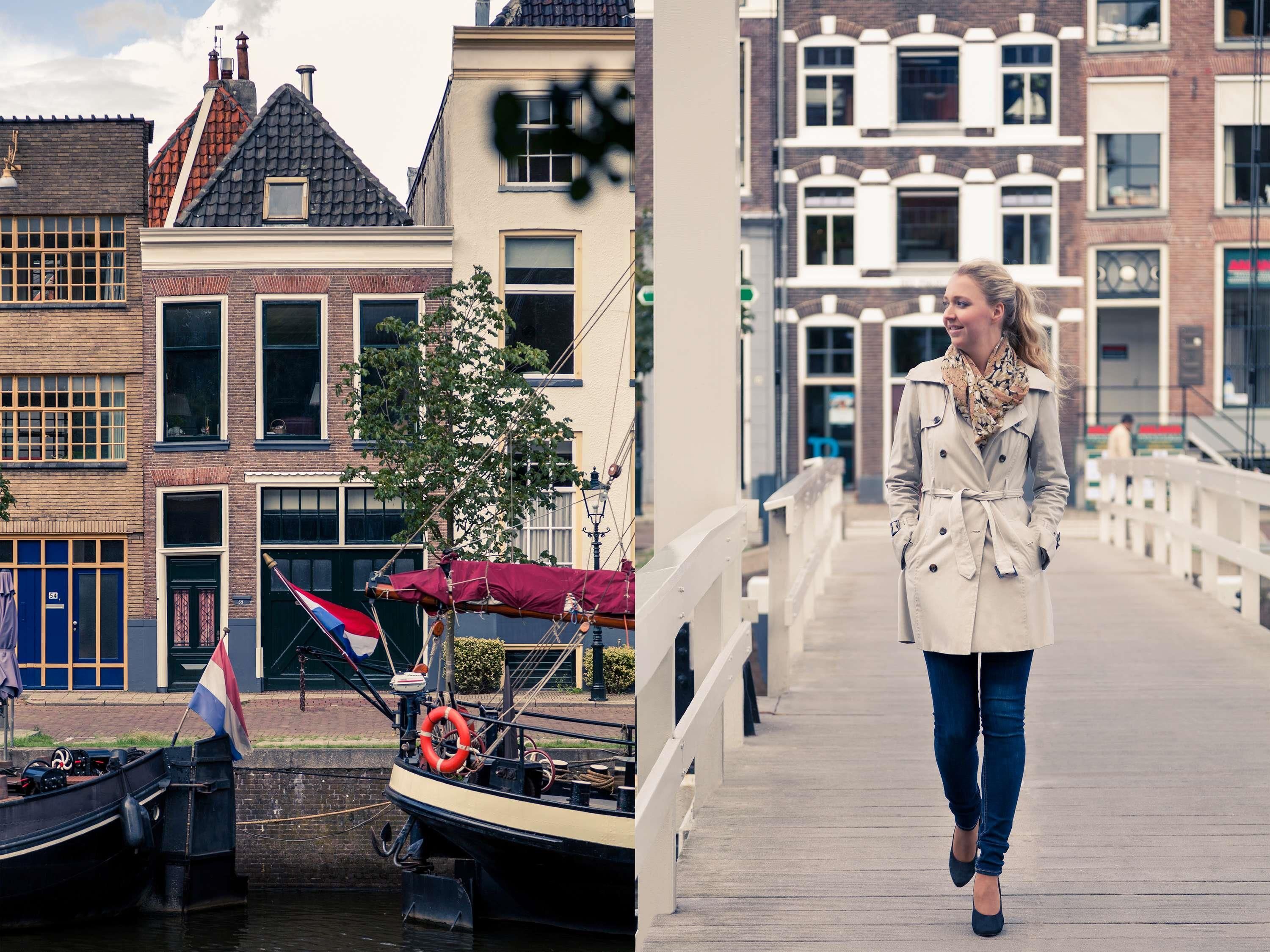 A canal with a boat docked, a pedestrian bridge, and traditional European buildings.