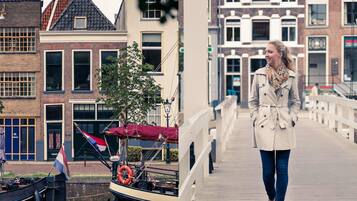 A canal with a boat docked, a pedestrian bridge, and traditional European buildings.