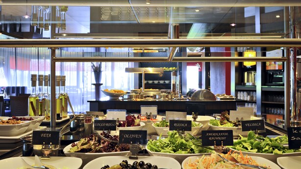 Ein Buffet mit verschiedenen Salaten und Speisen, darunter eine Oliven-Schale und ein Salat mit geriebenen Karotten.