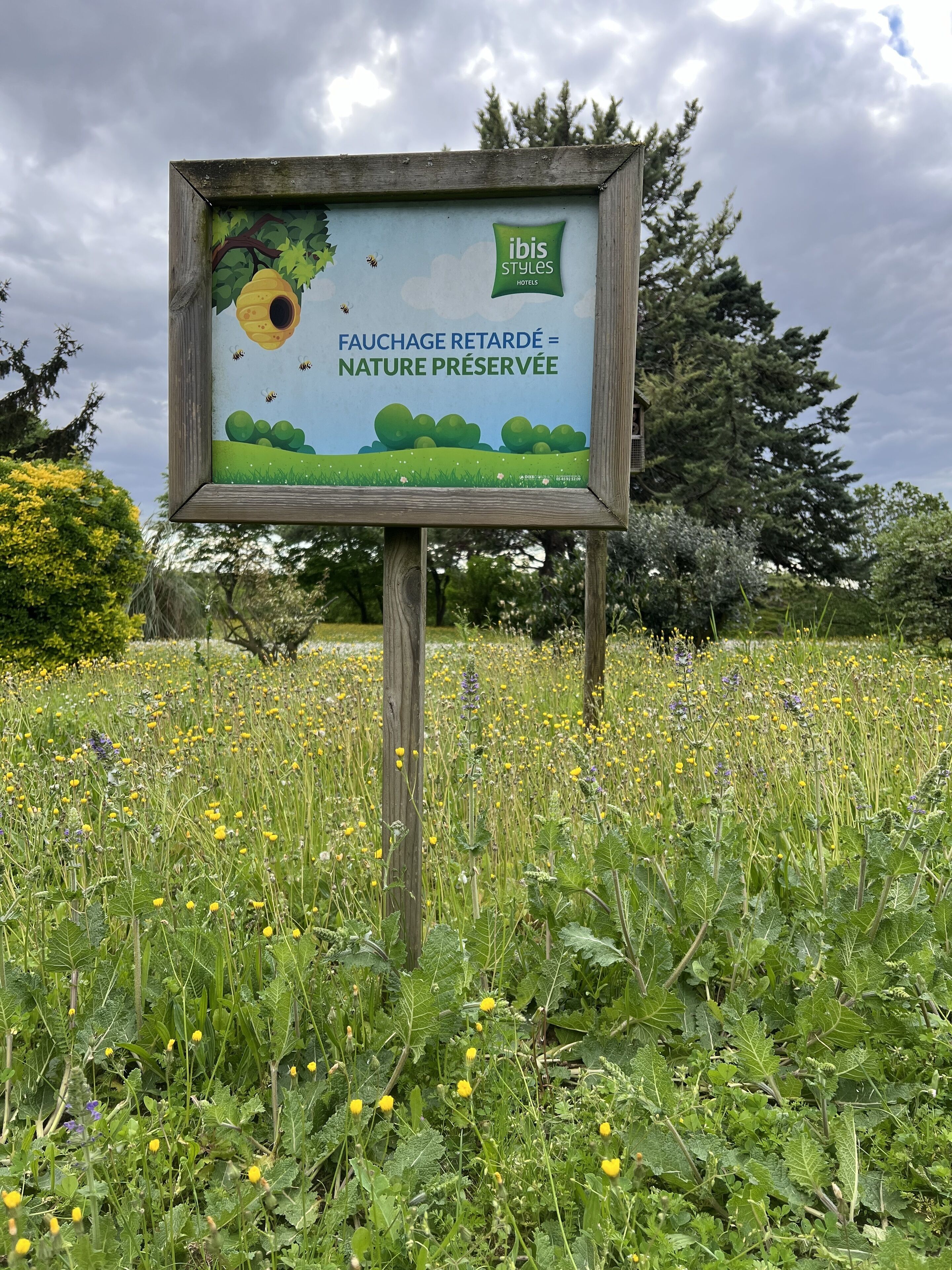 Ein Schild mit dem Text 'ibis styles hotels' und 'VERZÖGERTE ERNTE = EINGESCHÜTZTE NATUR'.