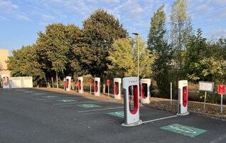 A parking area with multiple Tesla electric vehicle charging stations.