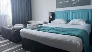 A hotel room with a bed, pillows, a headboard, a bedside table, a lamp, a window with curtains, and a wall decoration. - ibis Styles Angouleme Nord (Champniers)