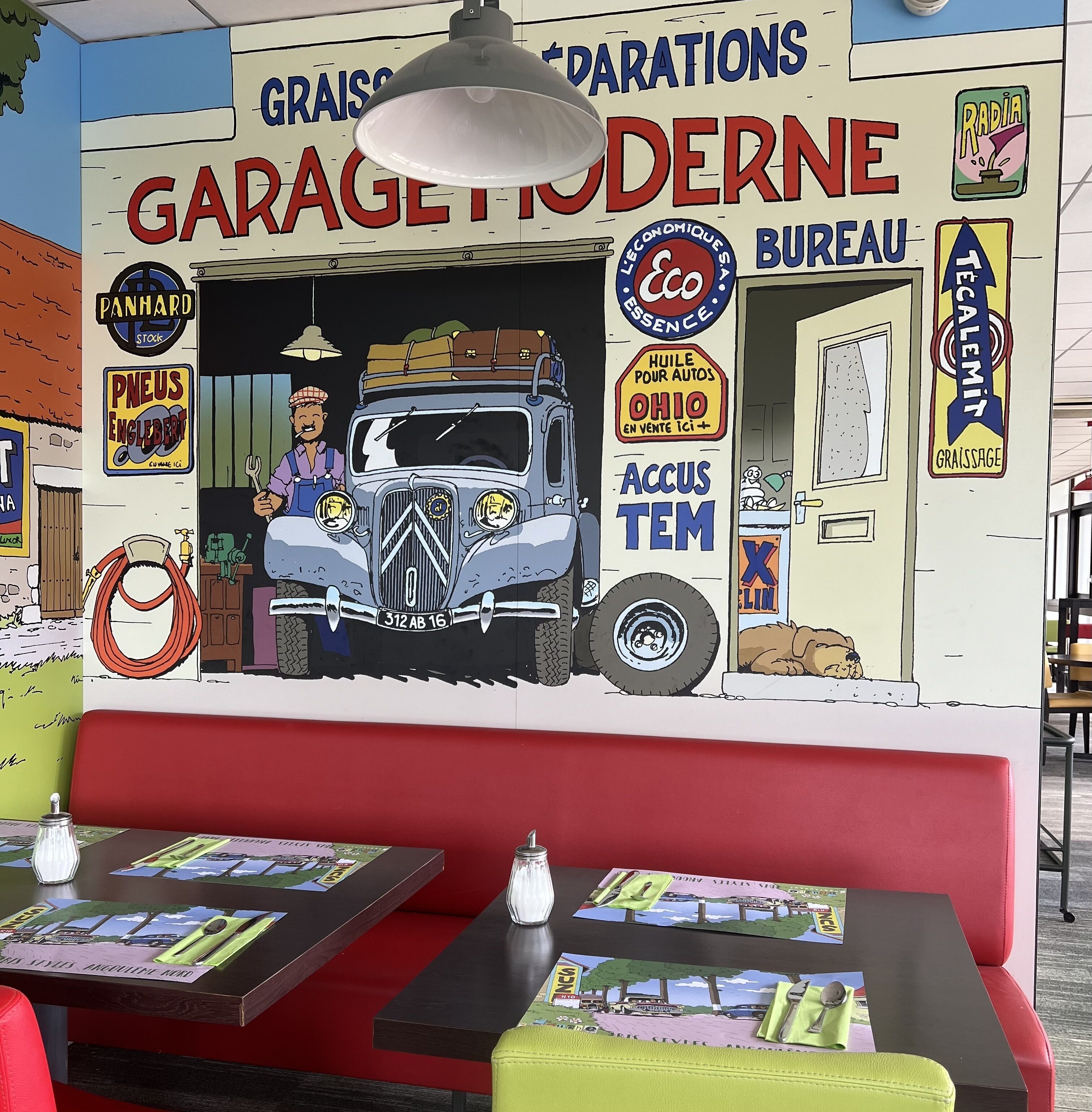A restaurant with a mural of a vintage car and various signs, including one for 'Garage Idérne'.