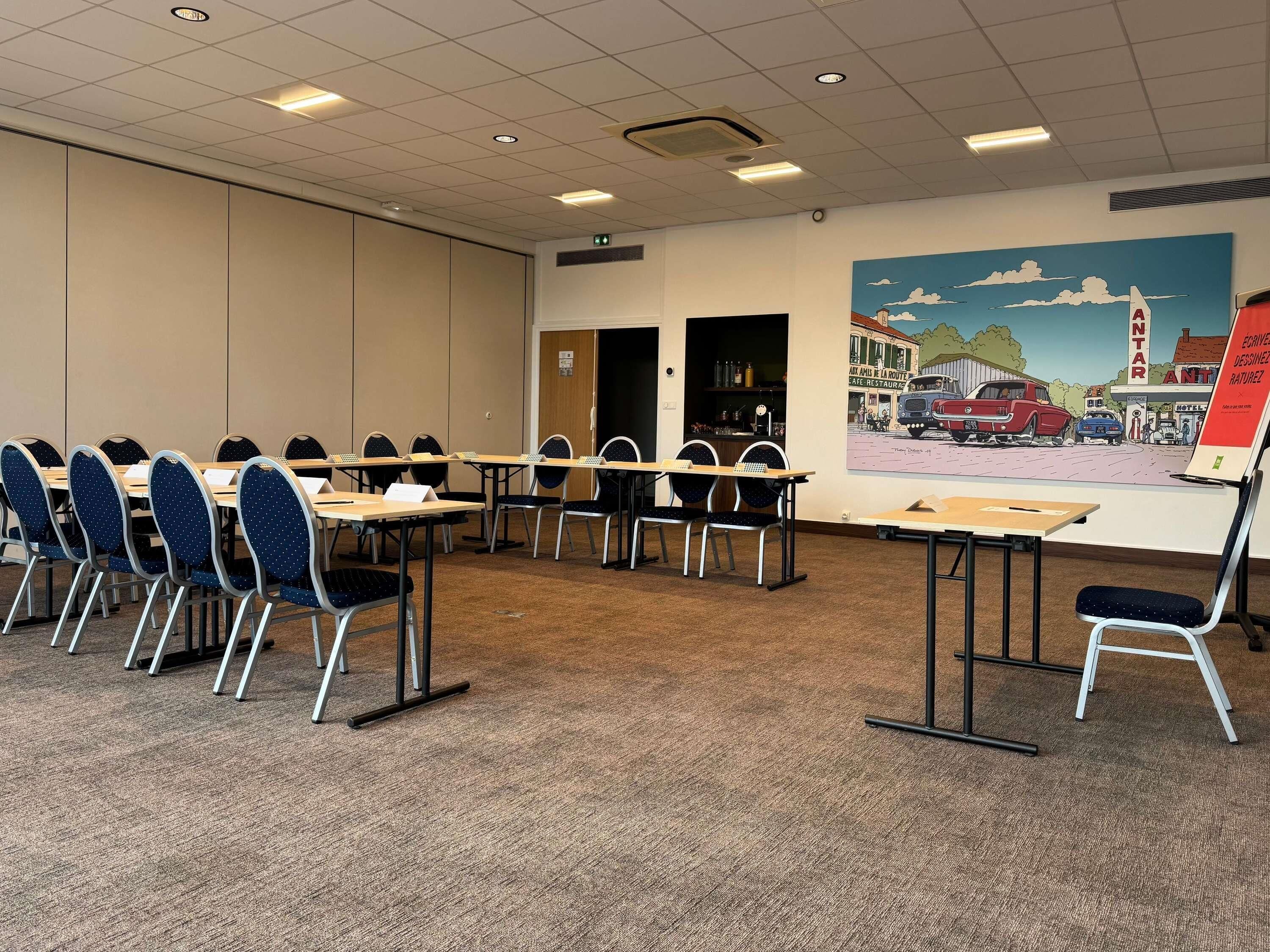 A conference room with tables and chairs, a painting on the wall, and a door leading to a kitchen area.