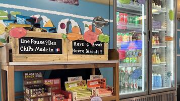 A snack display with various items like chips and biscuits, a poster, and a refrigerated display with beverages.
