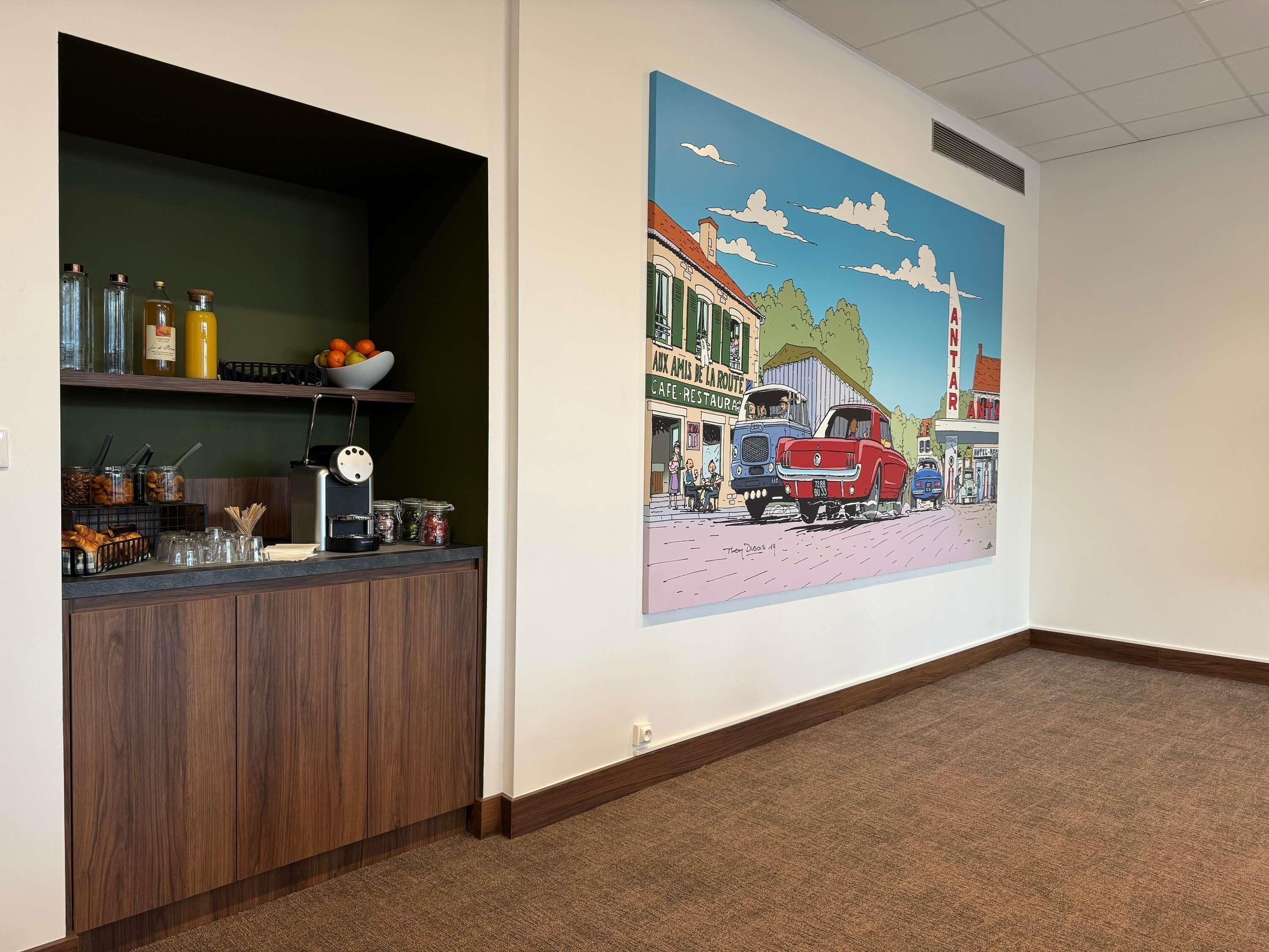A hotel lobby with a reception desk, a wall mural, and a carpeted floor.