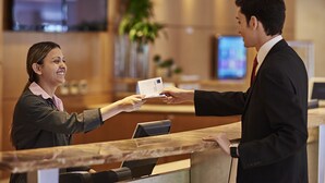 A reception desk with a woman handing a card to a man. - Novotel Sao Paulo Center Norte (São Paulo)