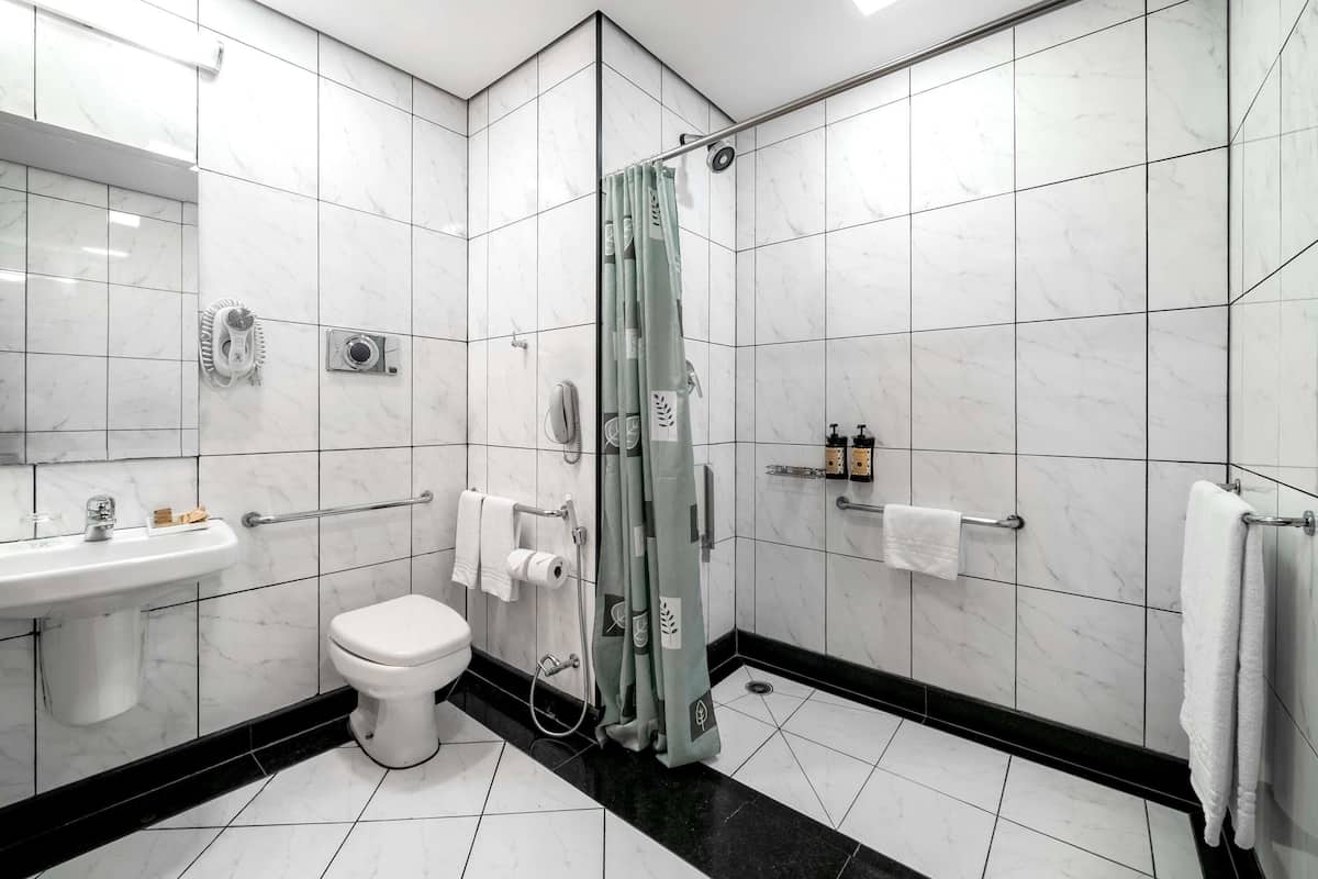 Casa de banho moderna com sanita, lavatório, chuveiro e suportes para toalhas.