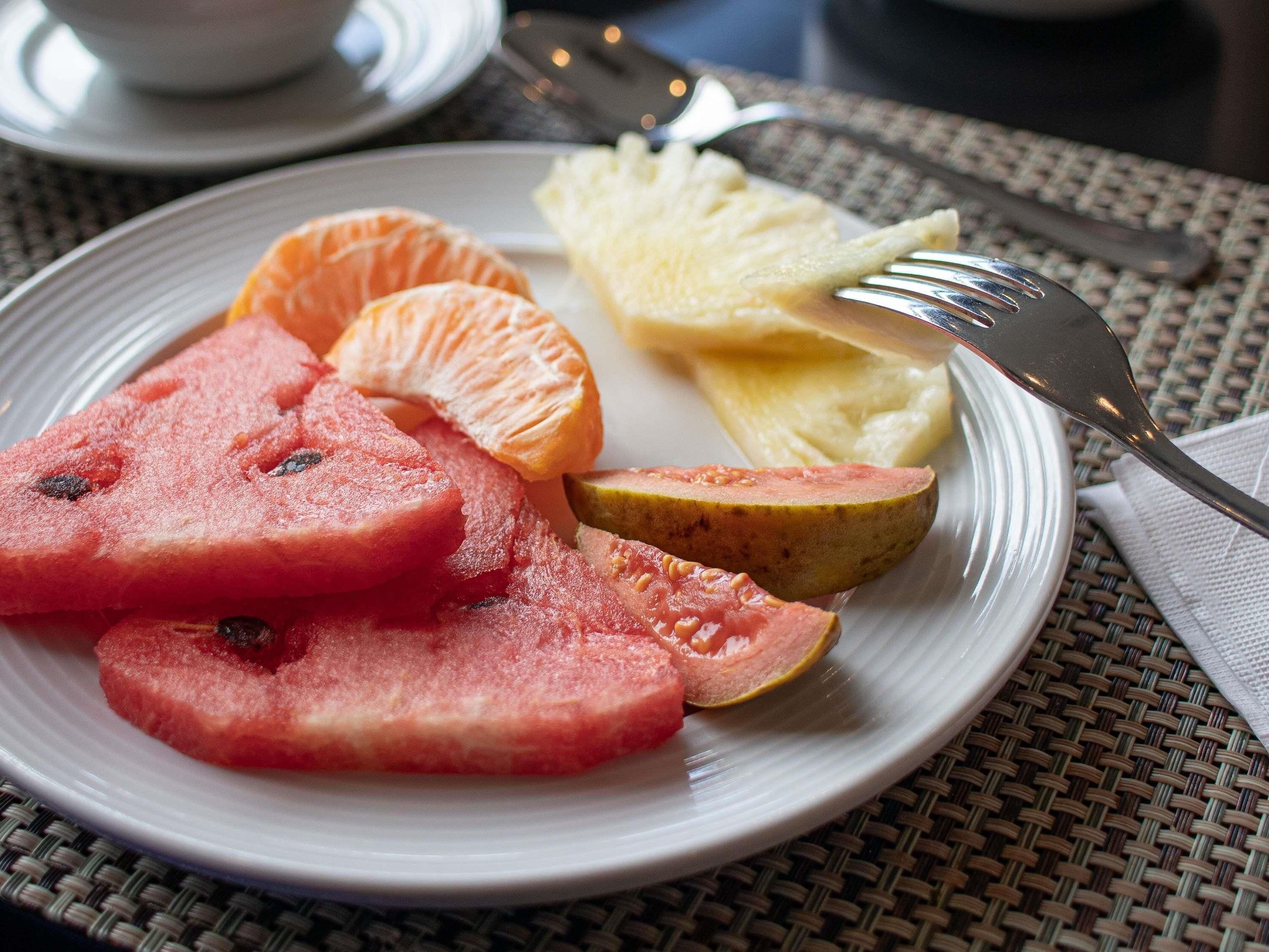 Un plato con sandía, naranja y huevos revueltos sobre una mesa.
