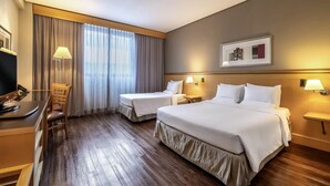 A hotel room with two beds, a desk with a computer, a chair, and a window with curtains. - Novotel Sao Paulo Center Norte (São Paulo)