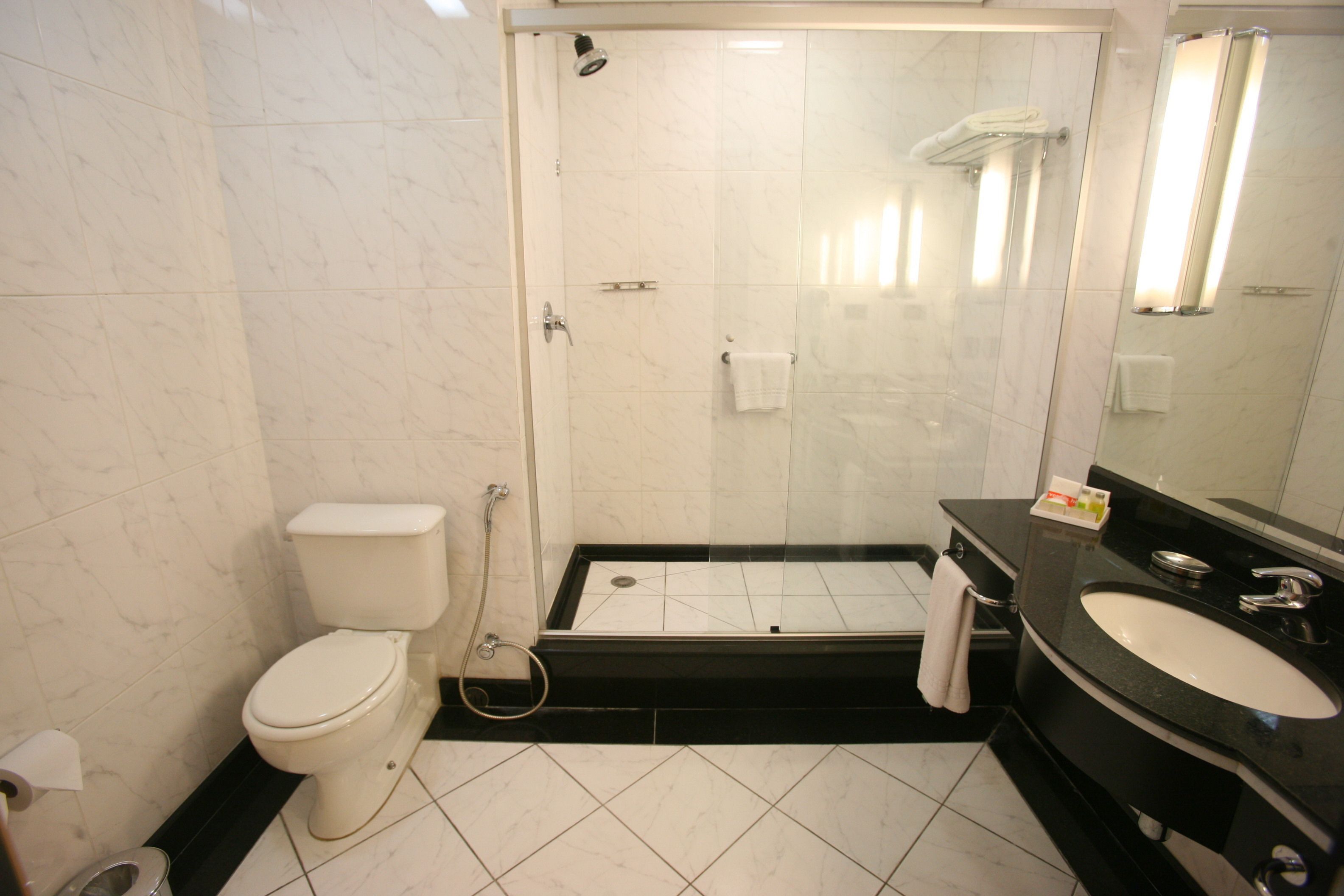 A modern bathroom with a toilet, shower, and sink.