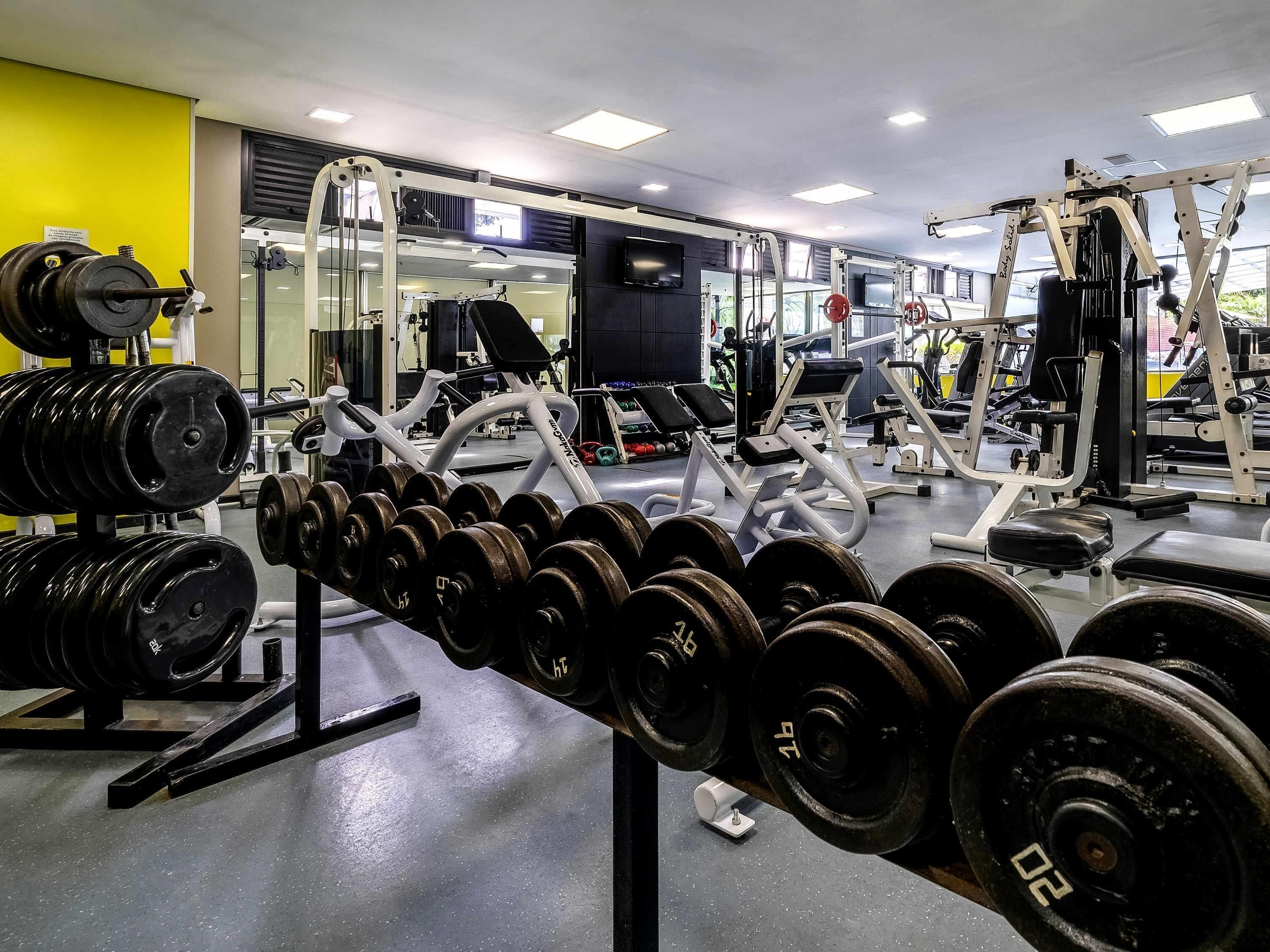 Ett gym med utrustning för styrketräning, speglar och träningsmaskiner.