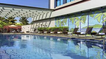 Una piscina al aire libre, sillones reclinables de piscina