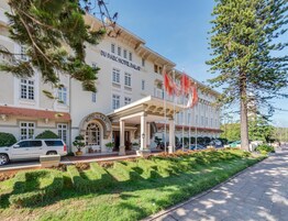 Un hotel con fachada clásica, un acceso cubierto y un asta con banderas.
