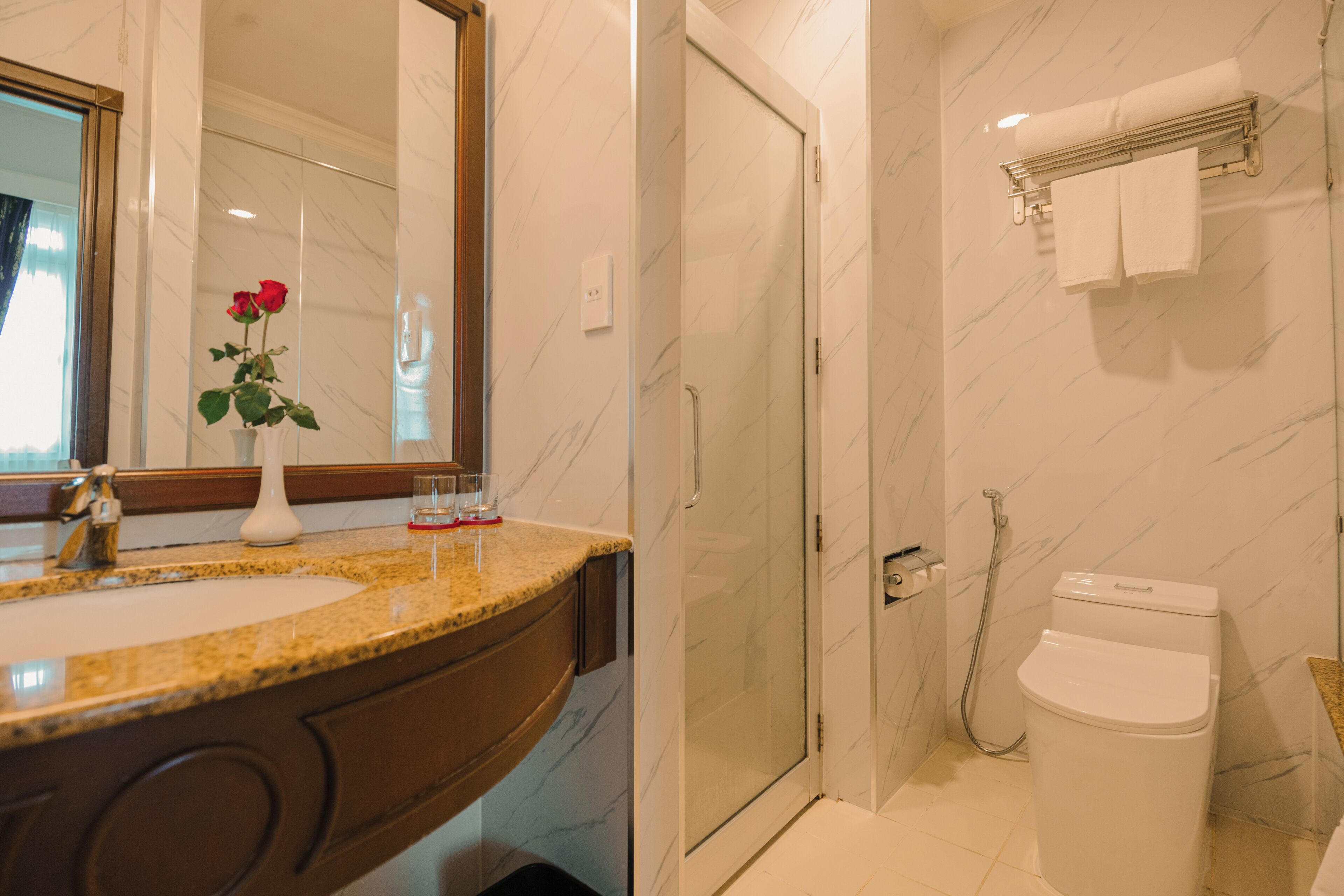 A bathroom with a marble sink, a shower, and a toilet.