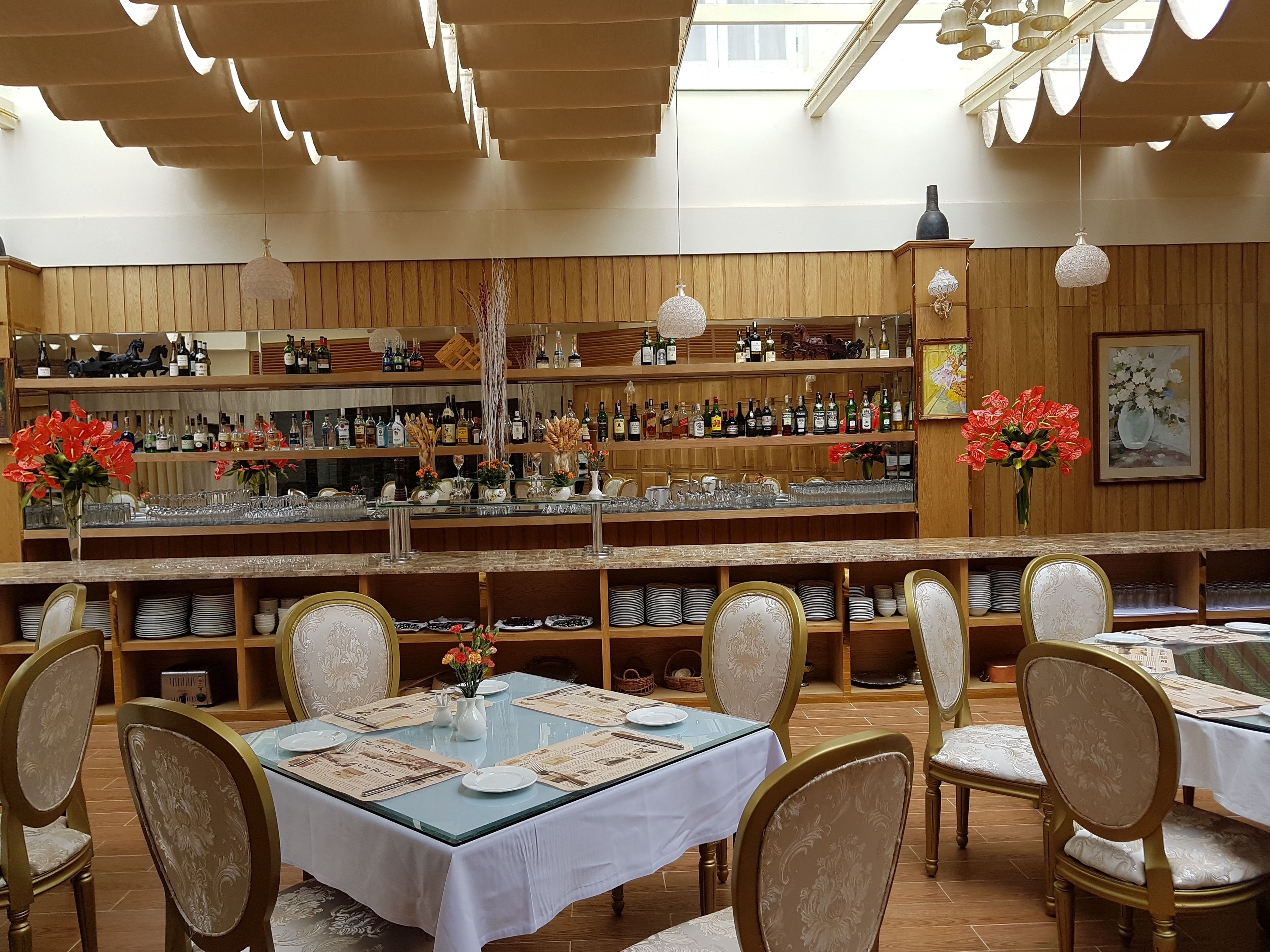 Un restaurante con área de bar, paneles de madera y una variedad de botellas y copas a la vista.