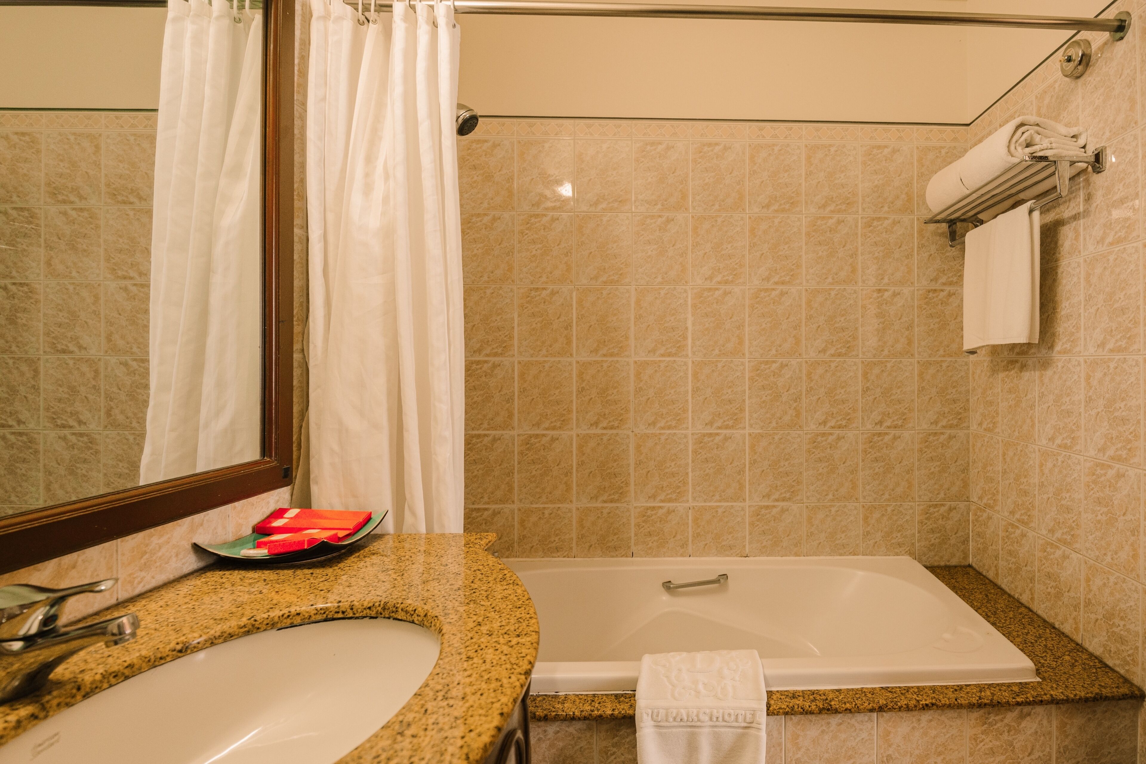 A bathroom with a sink, mirror, shower, and towel rack.