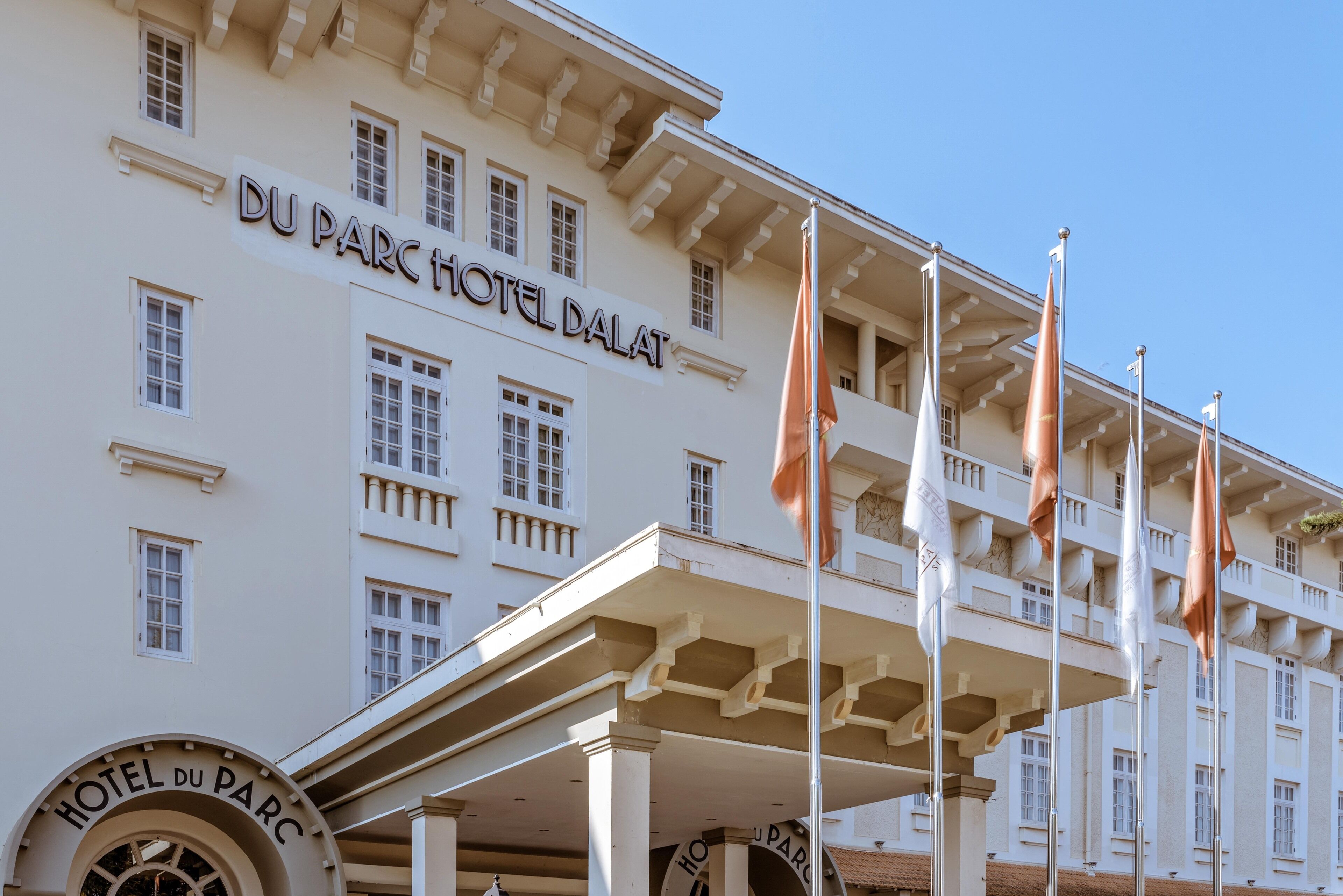 The exterior of the Hotel Du Parc, featuring a classical architectural style with multiple windows and a prominent entrance with flags.