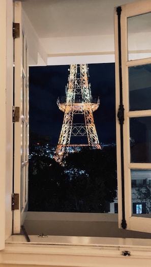 Une vue de la Tour Eiffel la nuit, prise à travers une fenêtre ouverte.