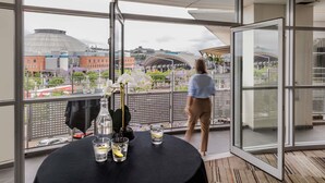 A room with a large window, a table with drinks, and a view of a cityscape.