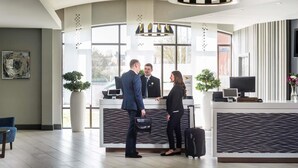 A reception area with a reception desk, a large window, and a modern chandelier. - Novotel Ipswich (Ipswich)