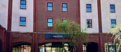 A hotel with a brick facade, multiple windows, and outdoor seating area with tables and chairs.