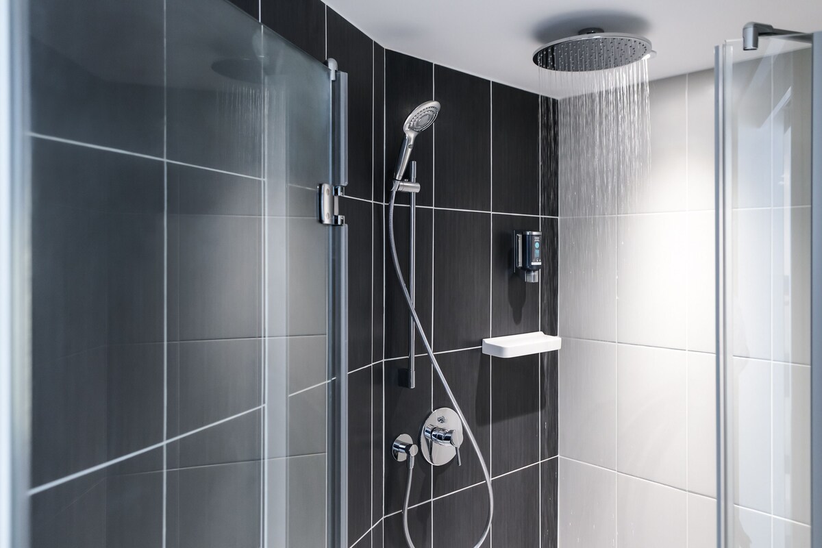 Una ducha moderna con cabezal de ducha tipo lluvia, cabezal de ducha manual y accesorio de ducha de mano.