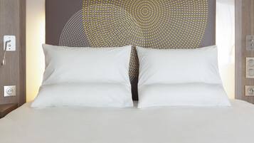 Een bed met witte kussens en een hoofdbord met een geometrisch patroon.